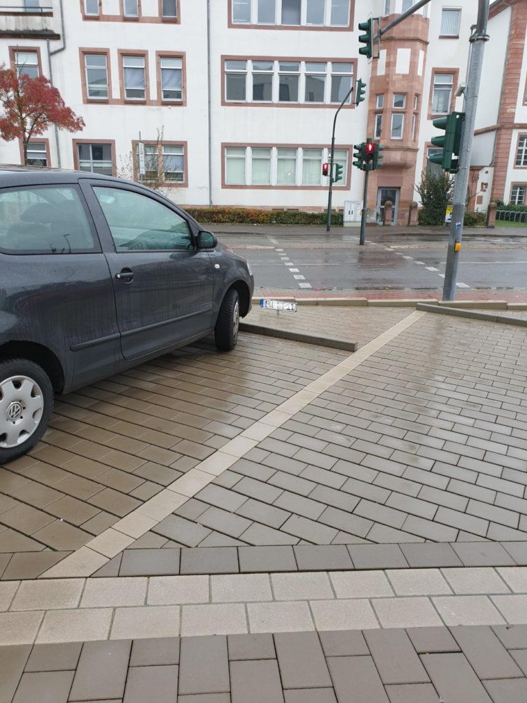 Das Bild zeigt einen Ausschnitt eines Parkplatzes, auf dem ein Auto steht. Weiße Streifen trennen die Parkplätze von einander ab.