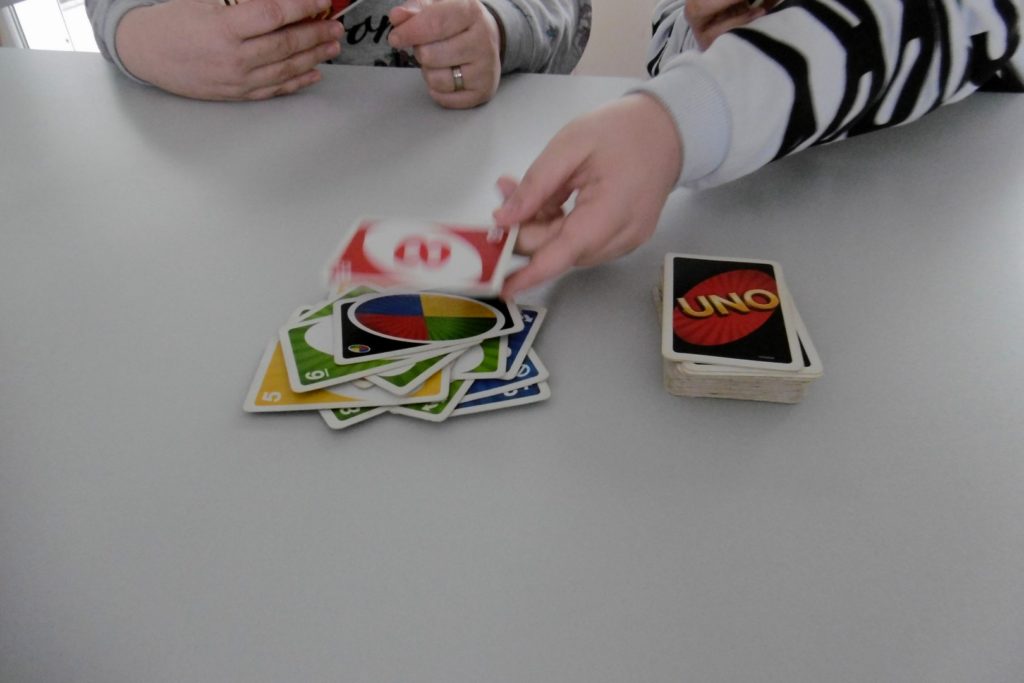 Mitten im Spiel. Ein Spieler legt eine rote Acht auf eine "Wünsch dir eine Farbe" Karte.