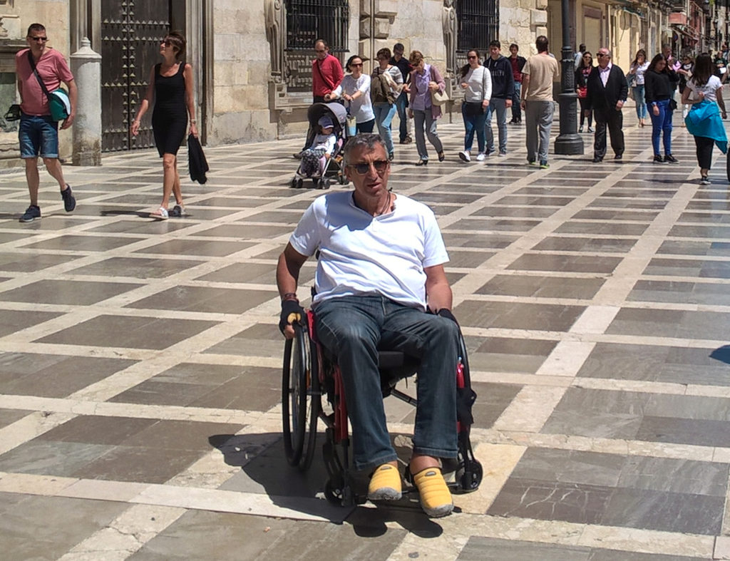 Jürgen im Rollstuhl sitzend im Mittelpunkt des Fotos in einer Einkaufsstraße in Andalusien