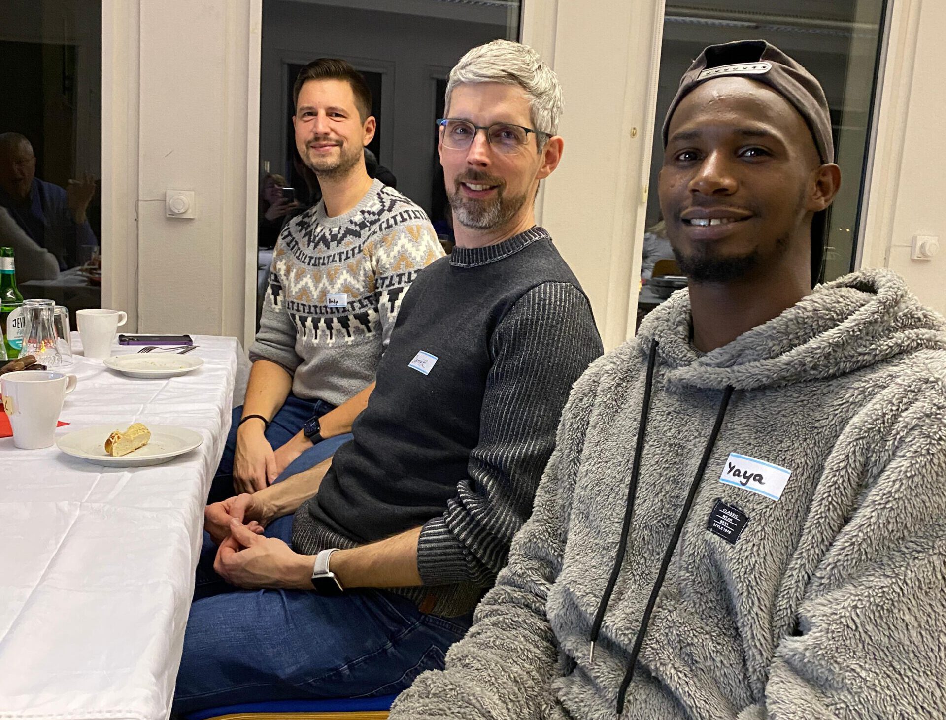 Andy, Daniel und Yaya sitzen nebeneinander.