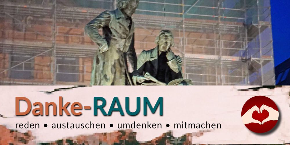 Demokratie-RAUM in Hanau. Das Denkmal der Brüder Grimm ist im Hintergrund zu sehen, vorne steht 