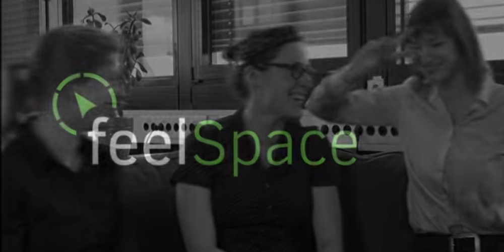 FeelSpace Navigürtel. Zu sehen ist das Logo von feelspace und dahinter drei der Entwicklerinnen.