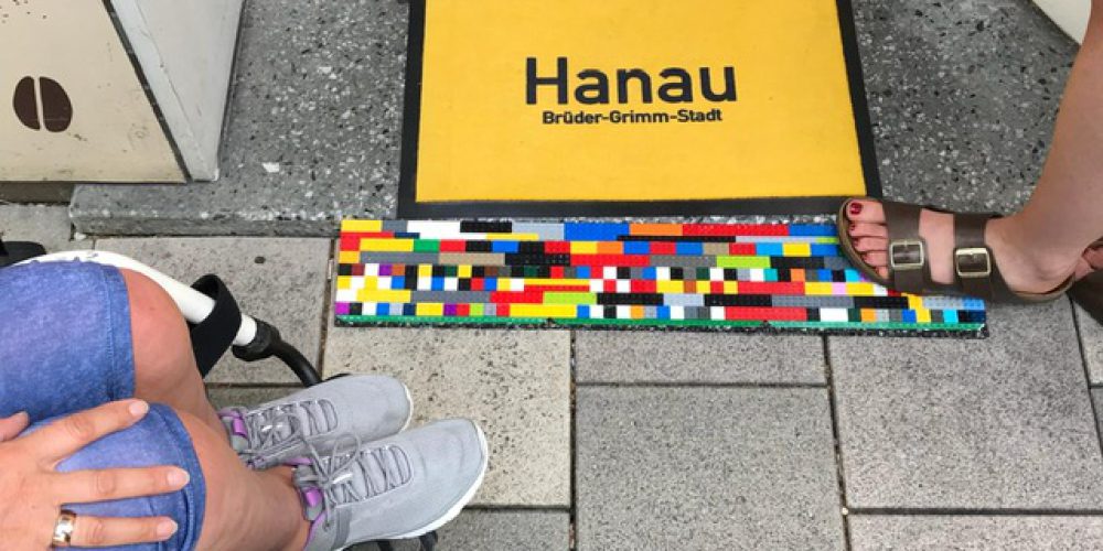 Auf der Türschwelle liegt die Fußmatte Hanau auf gelbem Grund. Davor und dahinter ist die bunte LEGO-Rampe zu erkennen.