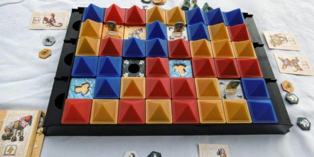 Das Spielbrett ist dominiert von farbigen Pyramiden und ein paar kleinen Aufstellern.