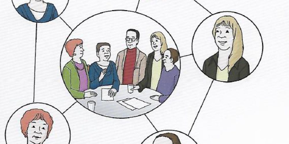 Das Bild zeigt fünf einzelne Personen in einem Kreis, die sich in der Mitte an einem Tisch vereinigen und in leichter Sprache kommunizieren.