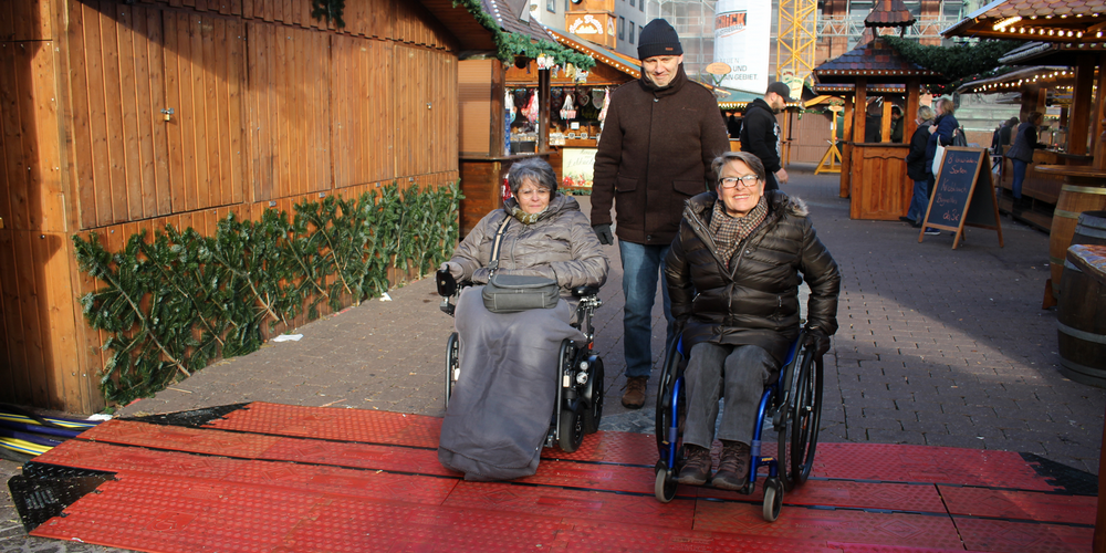 Zwei Frauen mit Rollstuhl auf dem Hanauer Weihnachtsmarkt