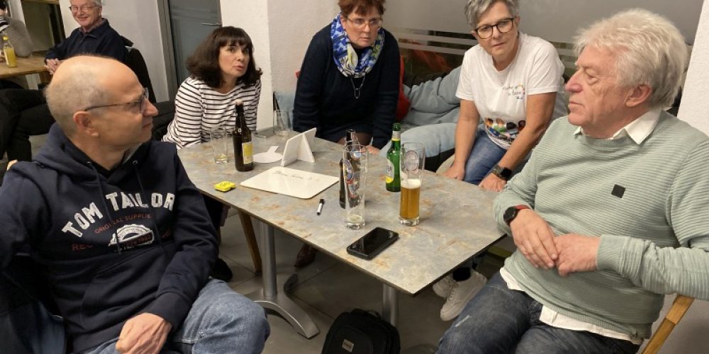 5 Personen sitzen um einen Tisch und diskutieren.