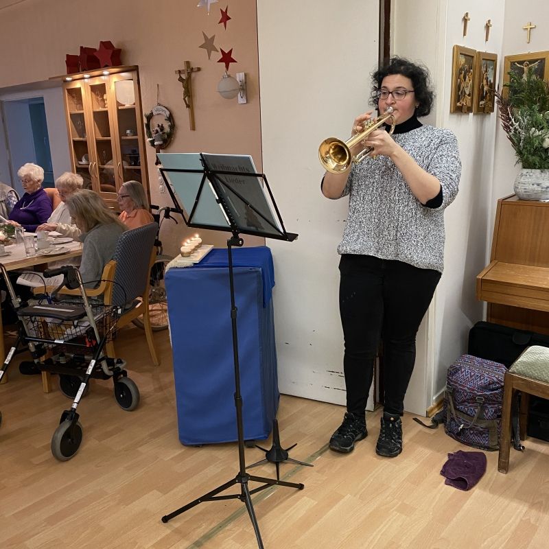 Cettina steht vor einem Notenständer und spielt auf ihrer Trompete Weihnachtslieder.