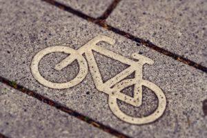Zu sehen ist ein Aussschnitt einer asphaltierten Straße. Auf einem Streifen ist in weißer Farbe das Symbol für ein Fahrrad zu sehen.