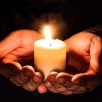 Zwei Hände halten eine Kerze als Zeichen des Mitgefühls für die Opfer des Attentats in Hanau am 19.02.2020
