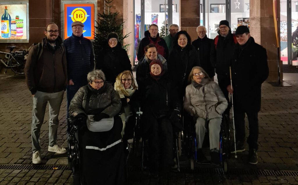 Mehrere Menschen mit und ohne Rollstuhl stehen vor dem Hanauer Rathaus