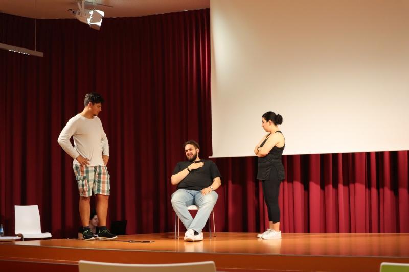 Szene aus dem interaktiven Theaterworkshop. 3 Personen stellen eine Szene mit Alltagsrassismus dar.